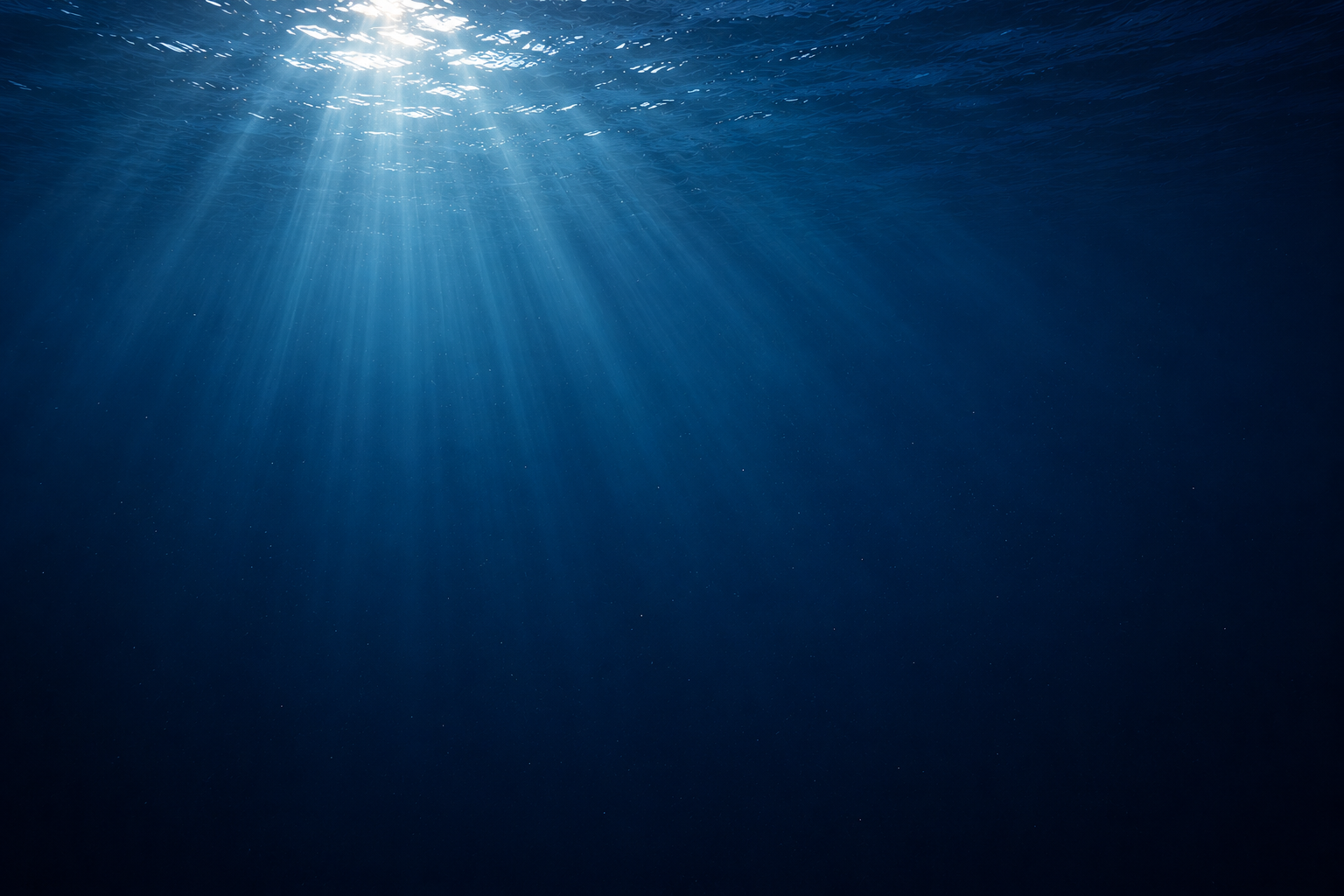 Looking up through deep blue water toward surface light